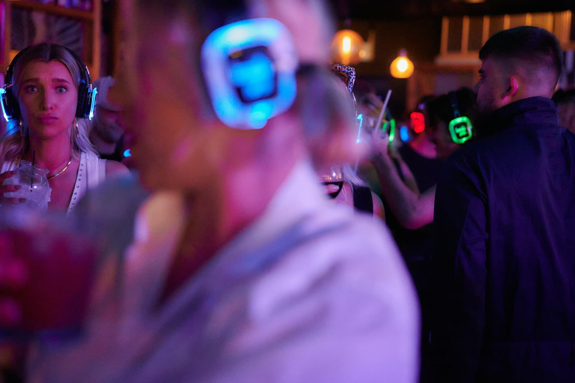 Guests at a bar wearing silent disco headphones lit blue, red and green, one colour for each channel